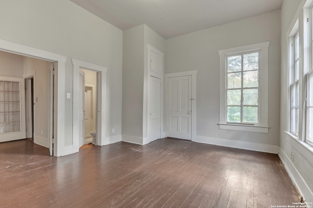 unfurnished bedroom featuring ensuite bath and dark hardwood / wood-style flooring