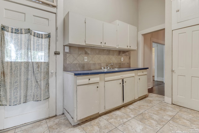 kitchen featuring white cabinets, light tile patterned floors, sink, and tasteful backsplash