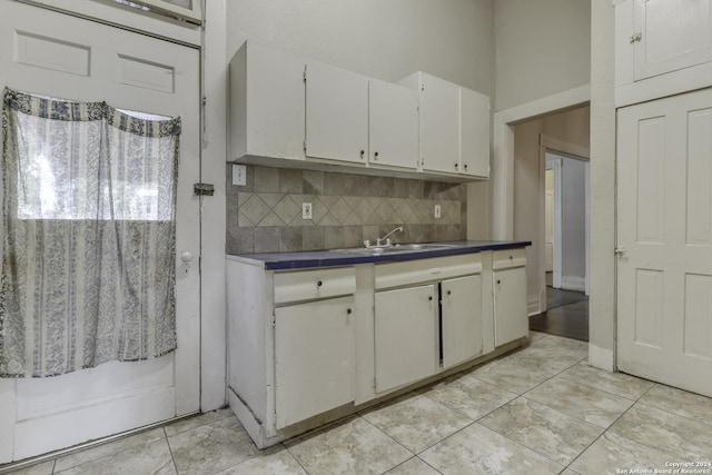 kitchen with dark countertops, tasteful backsplash, white cabinetry, and a sink