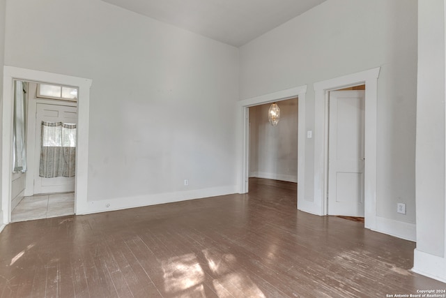 unfurnished room featuring dark hardwood / wood-style flooring, a towering ceiling, and a notable chandelier