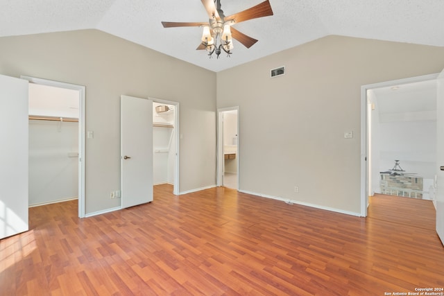 unfurnished bedroom with a spacious closet, light hardwood / wood-style floors, and vaulted ceiling