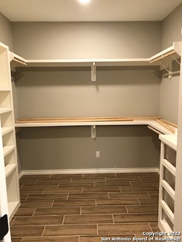 walk in closet with dark hardwood / wood-style flooring