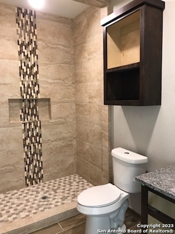 bathroom with a tile shower and toilet