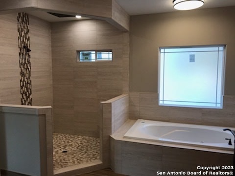 bathroom featuring independent shower and bath and a healthy amount of sunlight