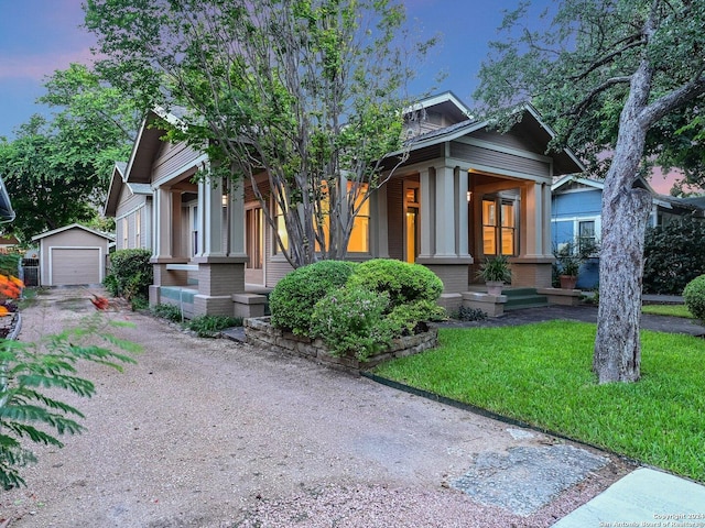 view of front facade featuring a lawn, a garage, and an outbuilding