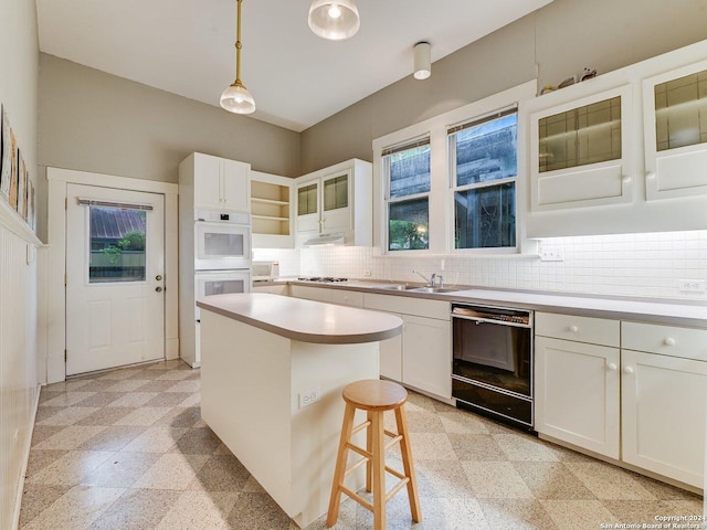 kitchen with backsplash, a kitchen island, pendant lighting, black dishwasher, and white cabinetry