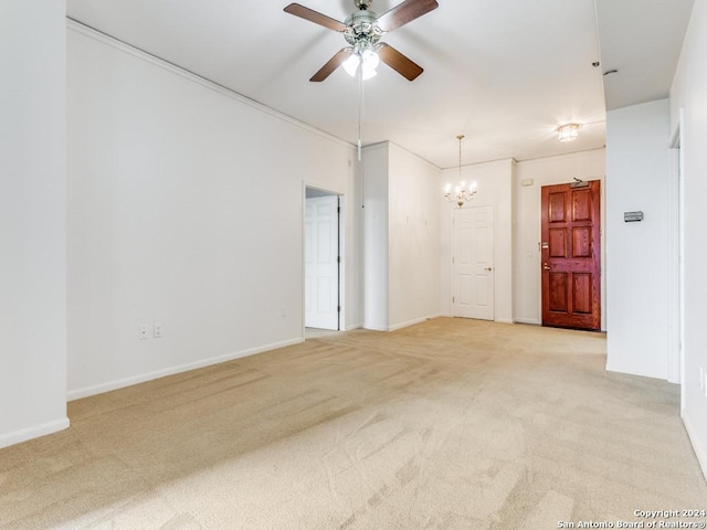 carpeted spare room featuring ceiling fan with notable chandelier