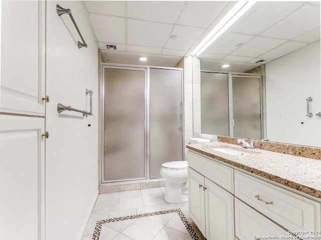 bathroom with a drop ceiling, tile patterned flooring, an enclosed shower, and vanity