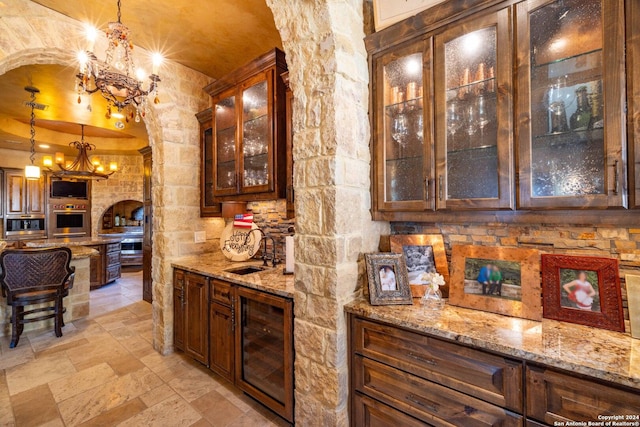 bar with a notable chandelier, decorative light fixtures, beverage cooler, and stainless steel oven