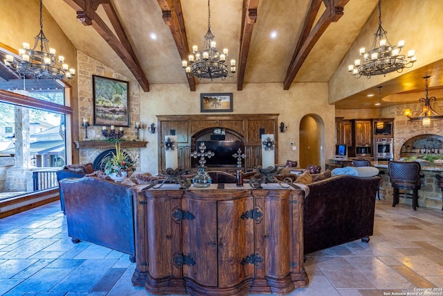 living room with beamed ceiling, high vaulted ceiling, a large fireplace, and an inviting chandelier