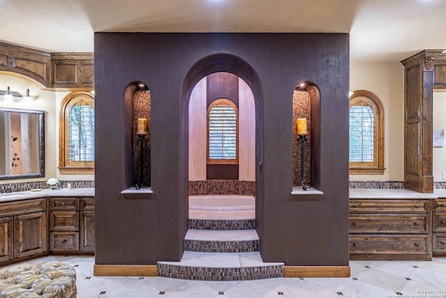 bathroom with vanity, a wealth of natural light, and a relaxing tiled tub