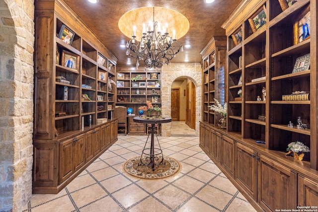 wine room featuring a notable chandelier, ornamental molding, and built in features