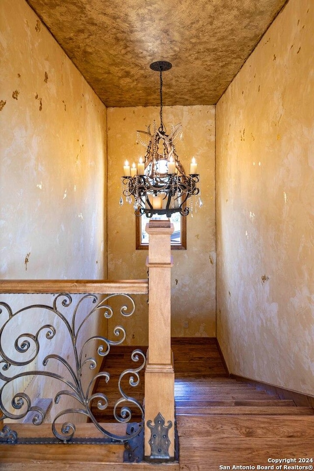 stairway featuring an inviting chandelier, hardwood / wood-style floors, and decorative columns