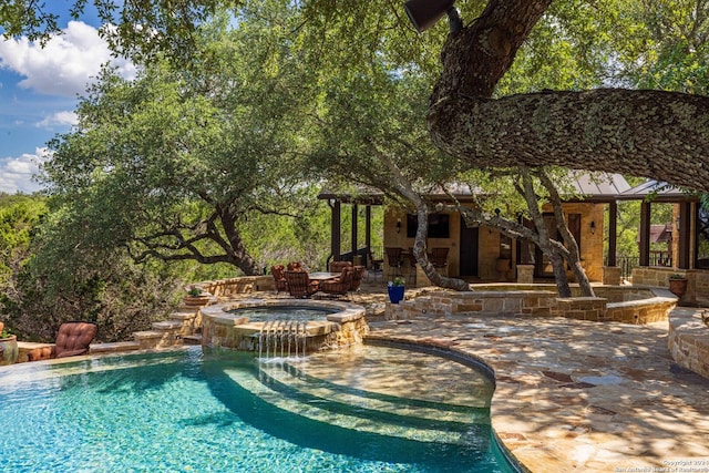 view of pool with an in ground hot tub, pool water feature, and a patio area