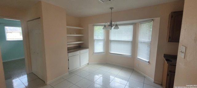 unfurnished dining area with light tile patterned floors, baseboards, built in features, and a notable chandelier