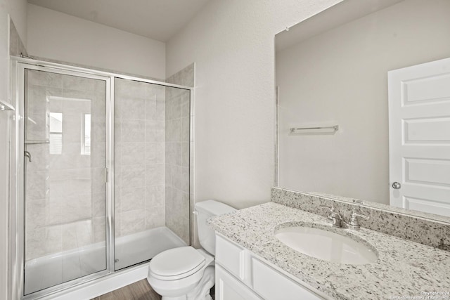 bathroom featuring toilet, hardwood / wood-style flooring, walk in shower, and vanity