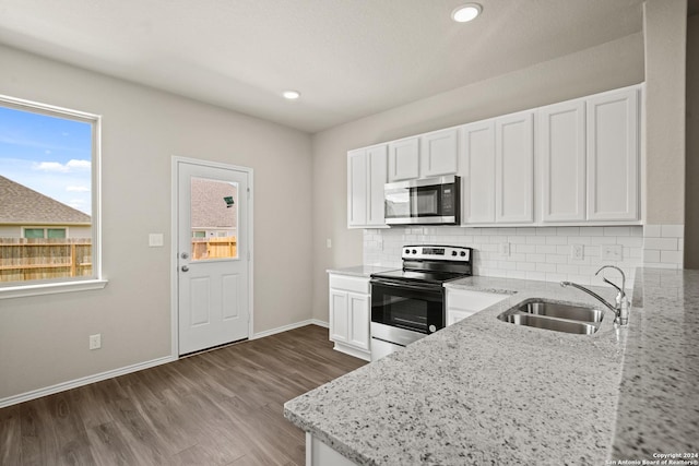 kitchen featuring appliances with stainless steel finishes, tasteful backsplash, light stone countertops, white cabinets, and sink