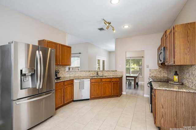 kitchen with light stone counters, sink, tasteful backsplash, and stainless steel appliances