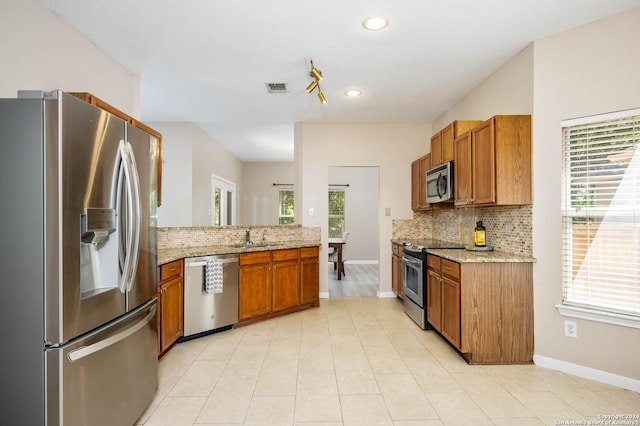 kitchen with light stone counters, sink, a wealth of natural light, and appliances with stainless steel finishes