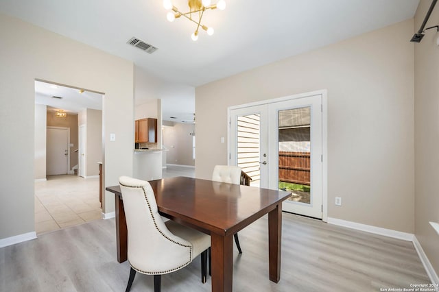 dining room with french doors, an inviting chandelier, and light wood-type flooring