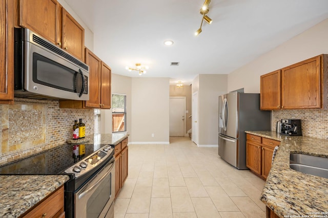 kitchen featuring light tile patterned flooring, appliances with stainless steel finishes, light stone countertops, and backsplash