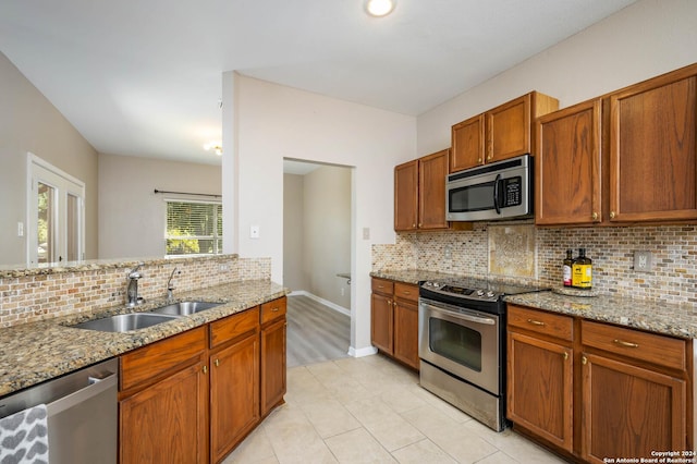 kitchen with light stone countertops, appliances with stainless steel finishes, sink, and backsplash