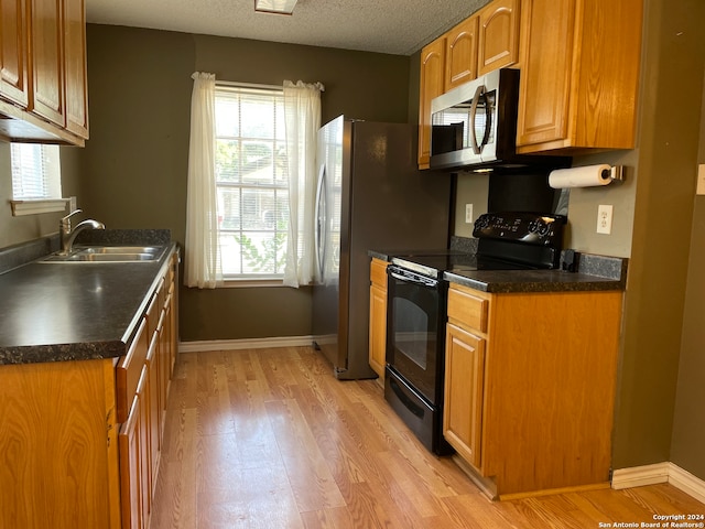 kitchen featuring electric range, sink, a textured ceiling, and light wood-type flooring