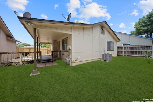 back of property with a deck, central AC, and a lawn