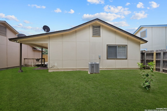 back of property featuring cooling unit and a yard