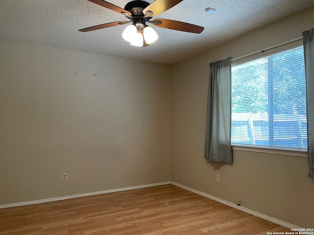 unfurnished room featuring a textured ceiling, light wood-type flooring, and ceiling fan