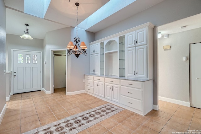 tiled dining area with an inviting chandelier, a skylight, and built in shelves