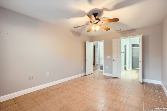 tiled spare room with ceiling fan