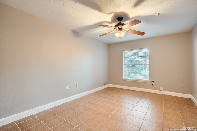 spare room featuring a textured ceiling, ceiling fan, and light tile patterned floors