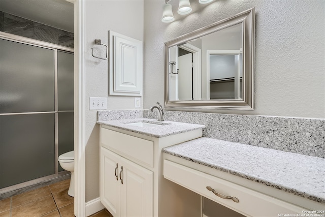 bathroom featuring toilet, tile patterned flooring, an enclosed shower, and vanity