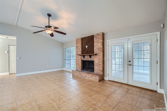 unfurnished living room with vaulted ceiling, a brick fireplace, ceiling fan, and light tile patterned floors