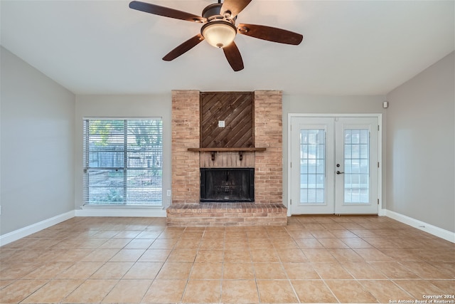 unfurnished living room featuring ceiling fan, french doors, a brick fireplace, and light tile patterned floors