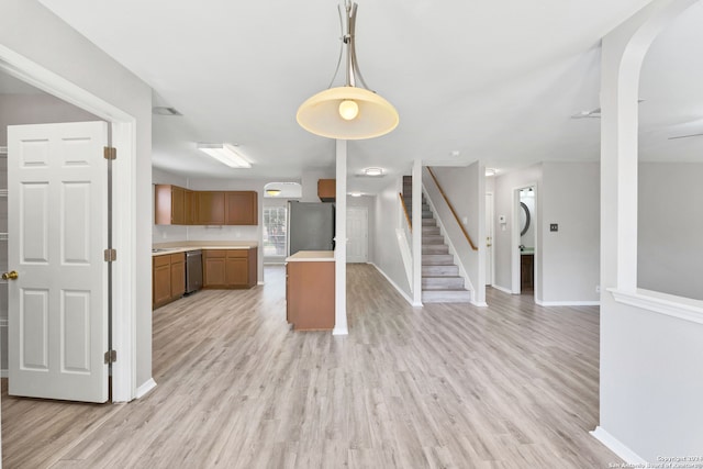 kitchen with appliances with stainless steel finishes, light wood-type flooring, and decorative light fixtures