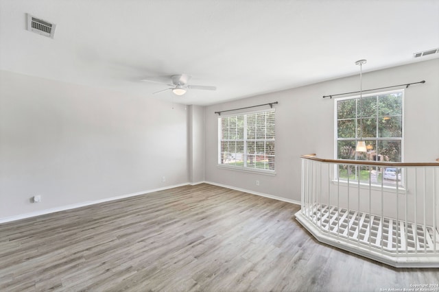 unfurnished room with hardwood / wood-style floors, ceiling fan, and a wealth of natural light