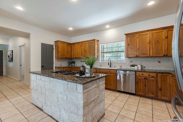 kitchen with dark stone counters, backsplash, appliances with stainless steel finishes, and sink