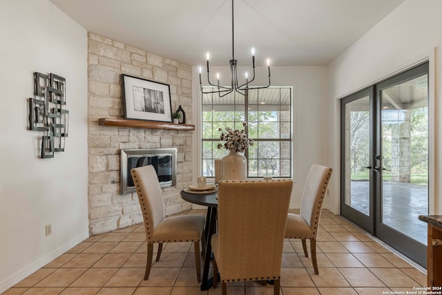 tiled dining room with a notable chandelier and a stone fireplace