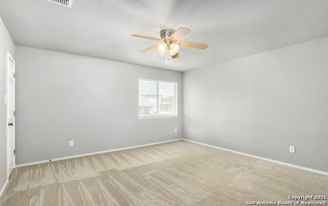 empty room with a textured ceiling, light colored carpet, and ceiling fan