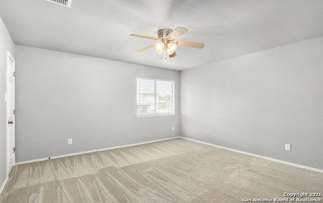 carpeted spare room featuring baseboards, a ceiling fan, and a textured ceiling