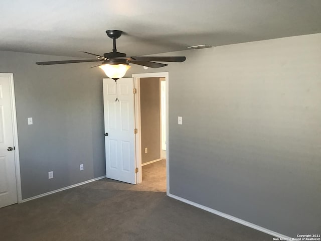 unfurnished room featuring baseboards, visible vents, dark carpet, and a ceiling fan