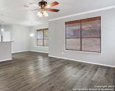 spare room with ceiling fan with notable chandelier, dark wood-type flooring, visible vents, baseboards, and crown molding