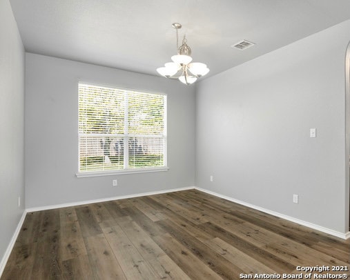 empty room featuring an inviting chandelier and dark hardwood / wood-style floors