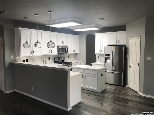 kitchen with arched walkways, appliances with stainless steel finishes, dark wood-type flooring, a peninsula, and light countertops