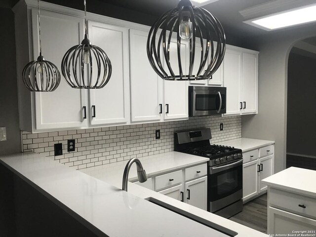 kitchen with appliances with stainless steel finishes, tasteful backsplash, white cabinets, and dark hardwood / wood-style floors