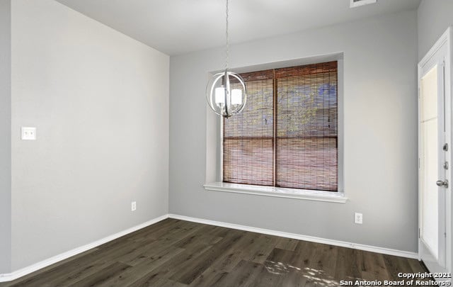 spare room with a chandelier and dark hardwood / wood-style floors