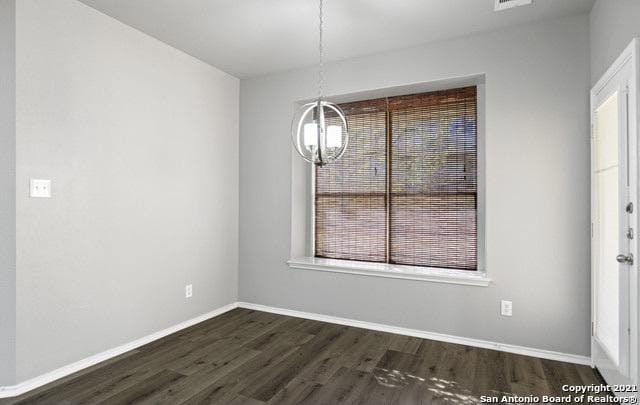 unfurnished dining area with dark wood-style floors, a chandelier, a wealth of natural light, and baseboards