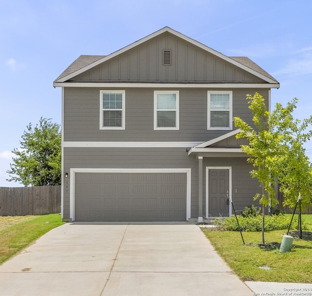 traditional-style house with a garage, fence, driveway, a front lawn, and board and batten siding